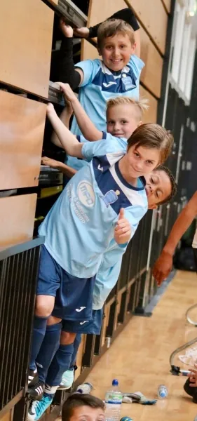 Young Braintree players smiling from the side of an indoor court