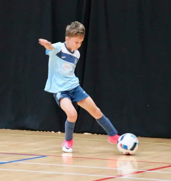 A young Braintree player striking a futsal ball on an indoor court