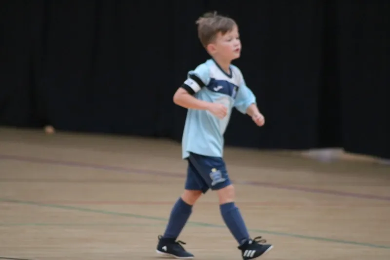 A player wearing a captain’s armband walking across the futsal court