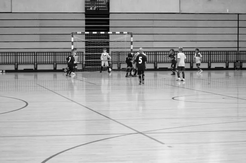 Black-and-white photograph of youth futsal action at the Copper Box